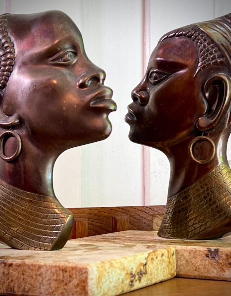 Bronze Bust Pair – Male and Female Pair of bronze African busts, Hagenauer Style, mounted on separate stone bases, mid-century decorative sculptures